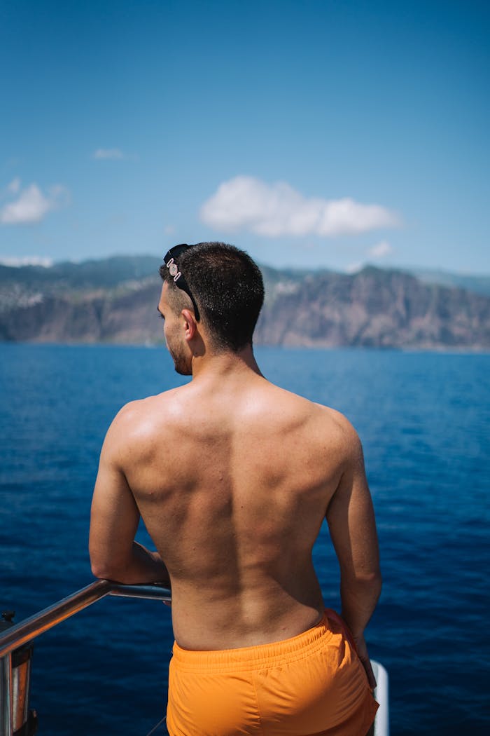 A man in orange shorts standing on the back of a boat